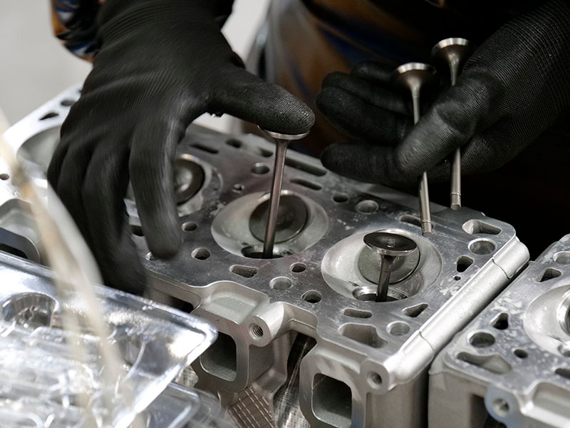 Técnico instalando válvulas em um cabeçote de cilindro na fábrica da Woda Auto.
