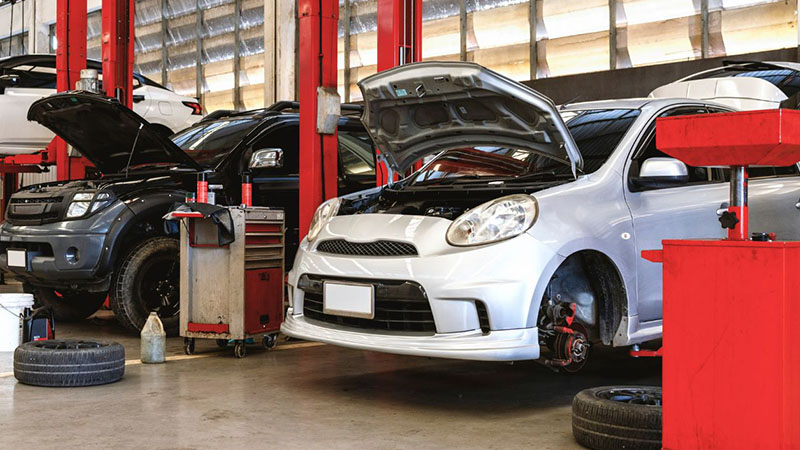 Auto repair workshop with car hood lifted.