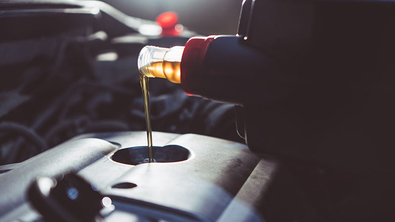 Fresh engine oil being poured into a diesel engine during an oil change.