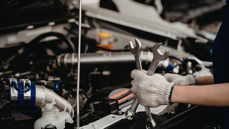 Mechanic repairing a diesel engine with a wrench and gloves.