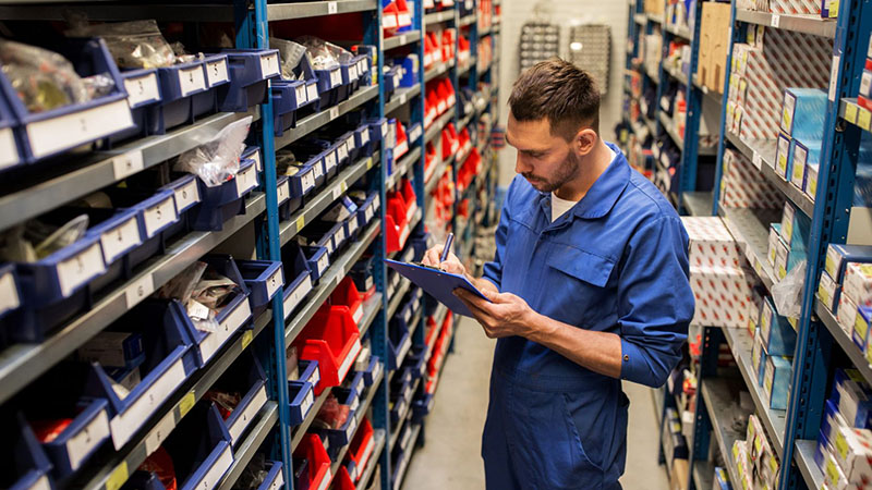 Auto mechanic checking engine inventory stock in warehouse.