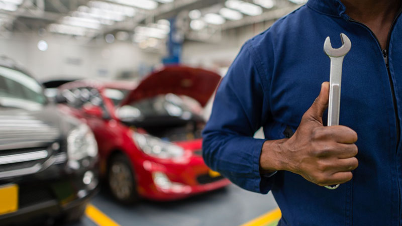 Mechanic holding tool at automotive repair shop during engine service.