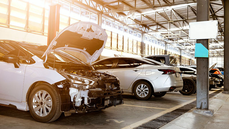 Car repair workshop with vehicles undergoing engine service and hood open.