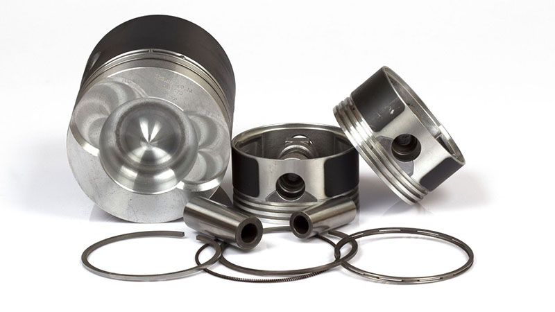 Close-up of automotive piston parts showing detailed metal components.