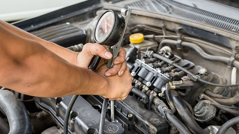 Mechanic performing an engine compression test with a diagnostic tester.