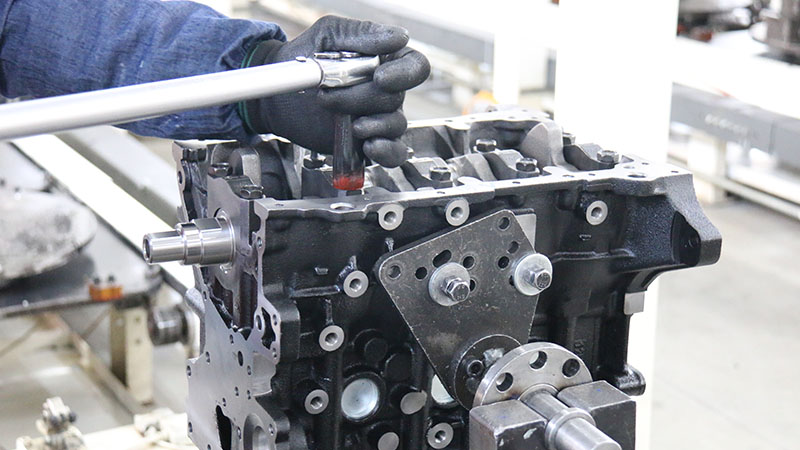 Mechanic installing a crankshaft into a cylinder block on the engine assembly line.
