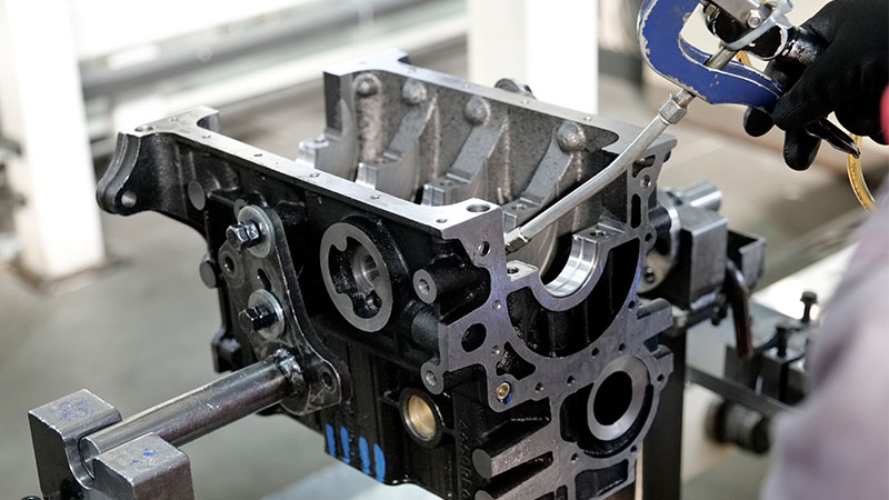 Mechanic inspecting an engine cylinder block on a factory production line.
