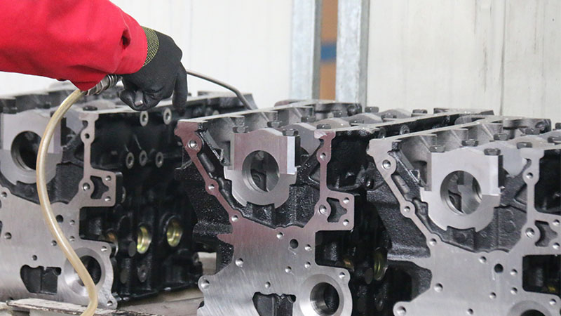 Close-up of a mechanic cleaning cylinder blocks on the production line.