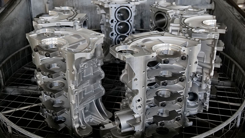 Engine cylinder blocks being cleaned during the manufacturing process.