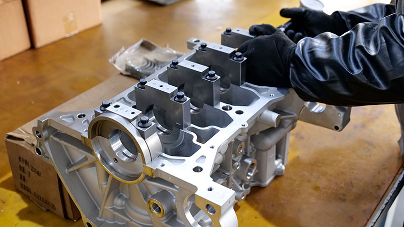 Mechanic inspecting a new engine cylinder block before engine assembly.