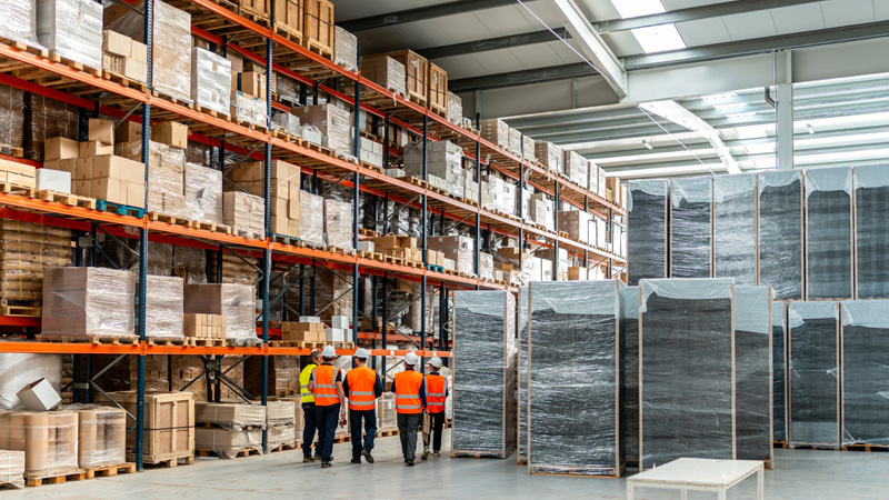 Des magasiniers inspectent un système de gestion des stocks logistiques.