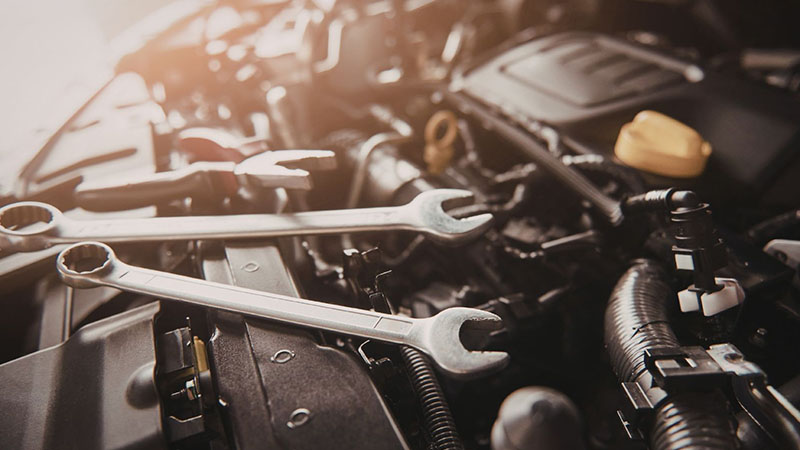 Car engine maintenance with tools on an open engine bay.