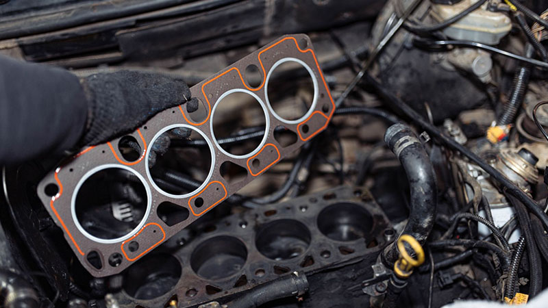 Mechanic replacing a cylinder head gasket during car engine repair.