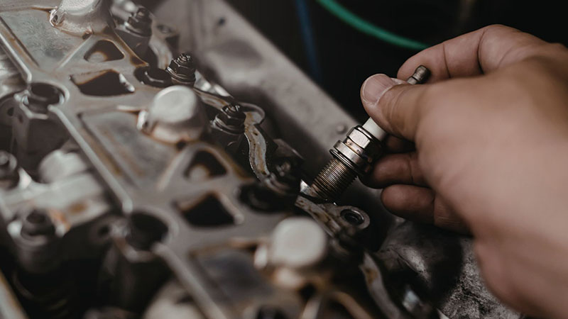 Mechanic installing a new spark plug into a car engine.
