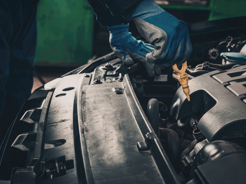 Mechanic checking engine oil level to diagnose oil consumption.