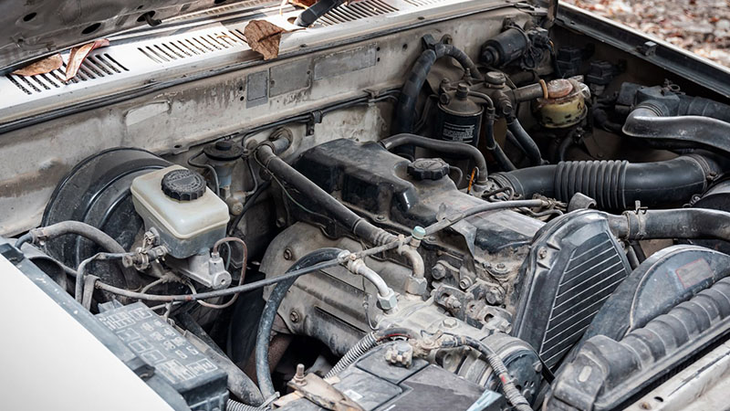 Close-up of old car engine showing wear related to oil consumption.