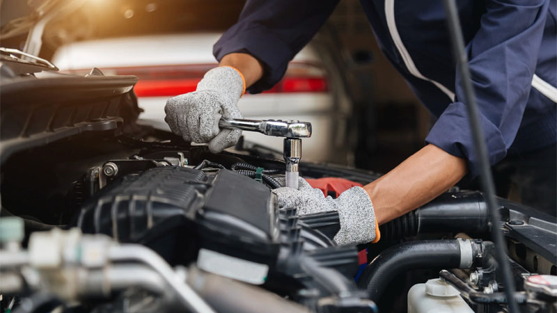 Vue rapprochée d'un mécanicien travaillant sur la réparation et l'entretien du moteur d'un véhicule.