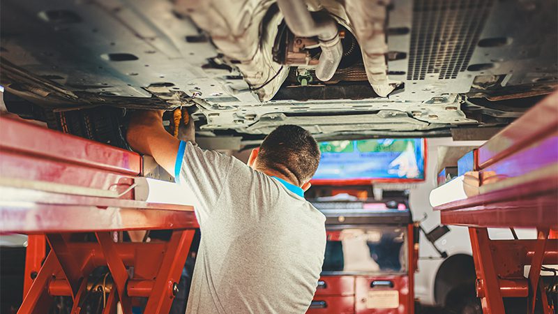 A mechanic working on a truck engine, performing maintenance or repairs.