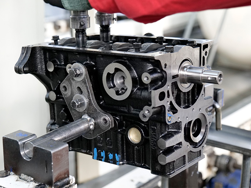 Mechanic working on engine assembly line at automotive factory for engine supplier.