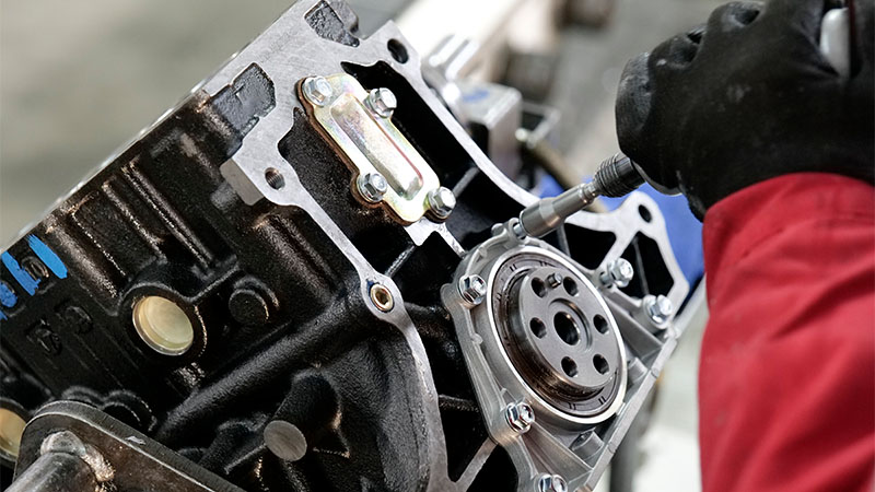 Mechanic assembling an automotive engine in factory workshop.