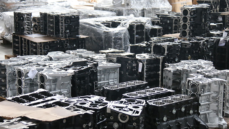 Various cylinder heads and engine blocks displayed in automotive parts warehouse.