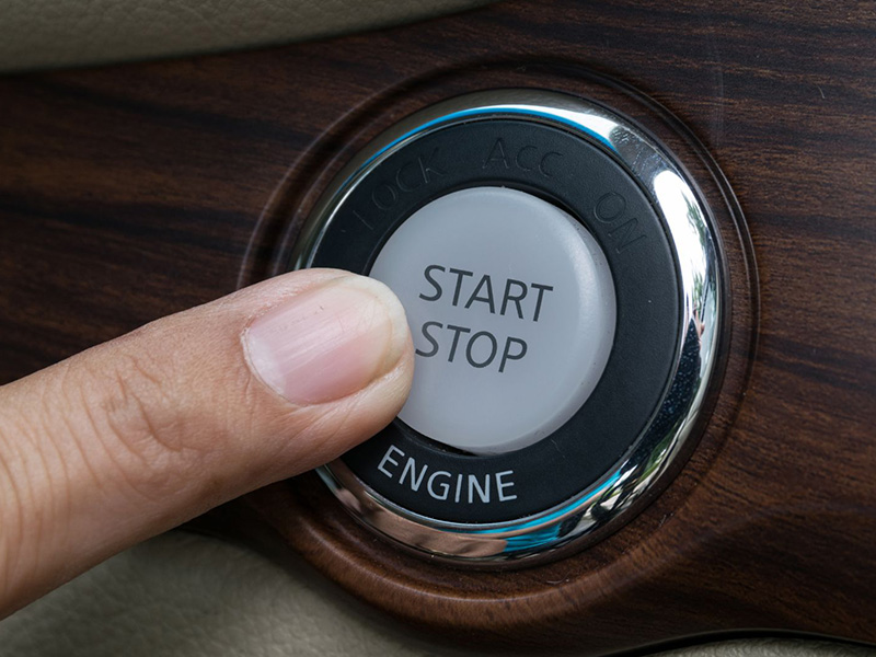 Driver pressing the engine start button of a car to start the engine.