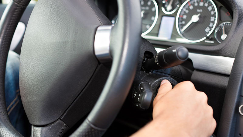 Man turning the ignition key in a car to start the engine during troubleshooting.
