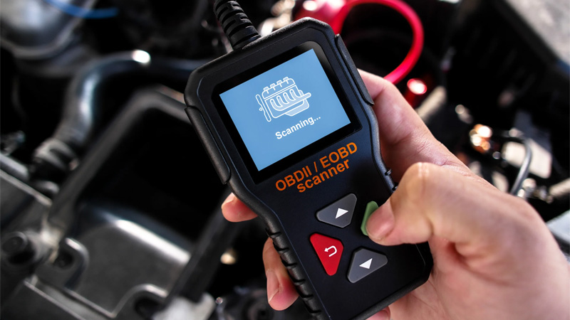 Mécanicien automobile utilisant un scanner OBD-II portable pour le diagnostic du véhicule et le dépannage du moteur.