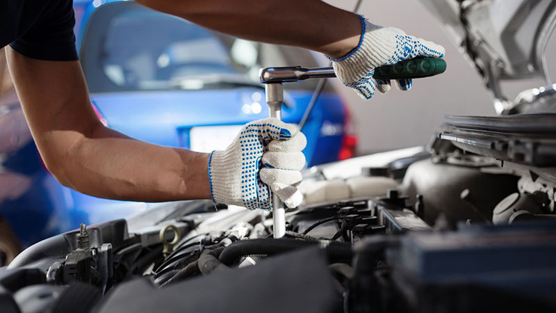 Mechanic working on engine in auto repair garage.
