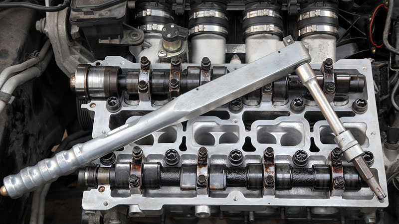 Automotive cylinder head servicing with technician inspecting components.