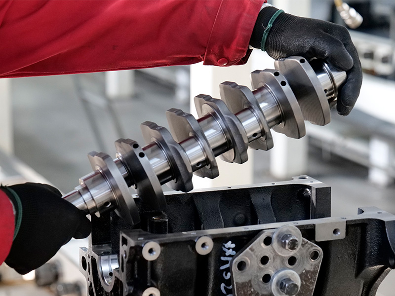 mechanic installing a crankshaft into an engine cylinder block during assembly.
