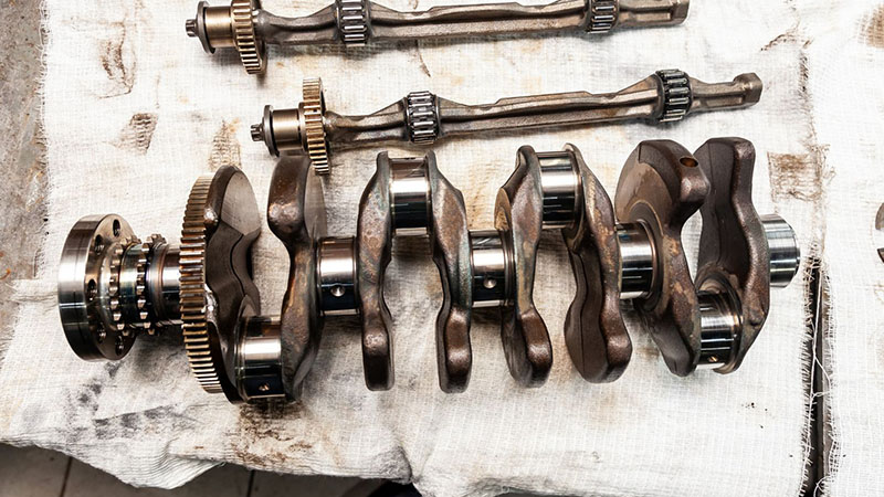 Car crankshaft removed from engine for replacement during repair.
