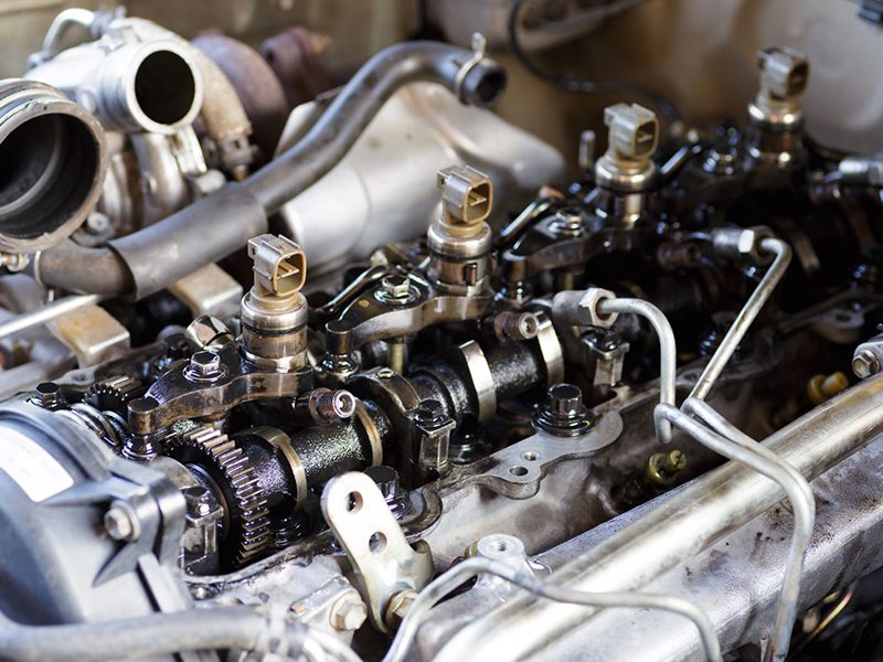 Close-up of engine repair with fuel injection system and diesel car parts on workshop track.