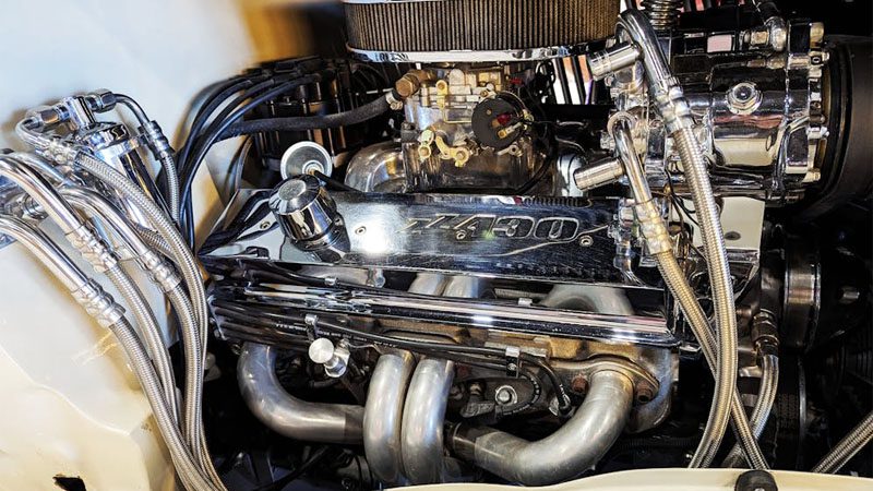 Подробный вид хромированного двигателя старинного автомобиля, подчеркивающий механические компоненты, карбюраторную систему и классический дизайн.