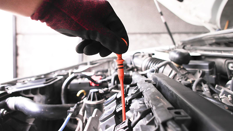 Mechanic checking the engine oil level with a dipstick.