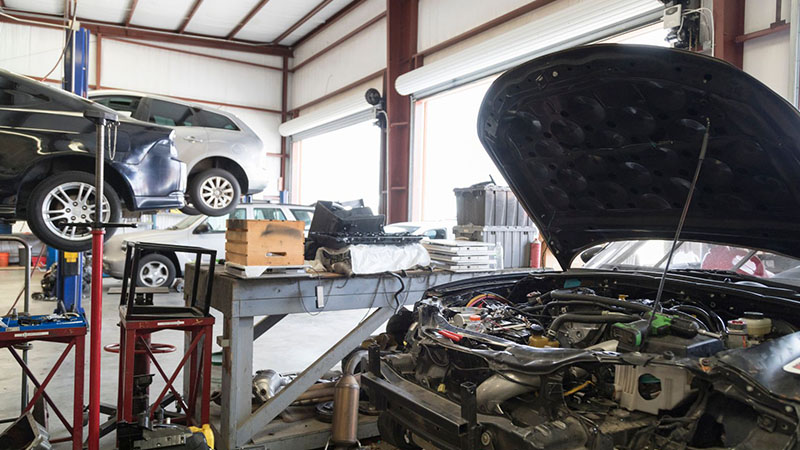 Car with the hood open in an auto repair garage, ready for engine replacement.
