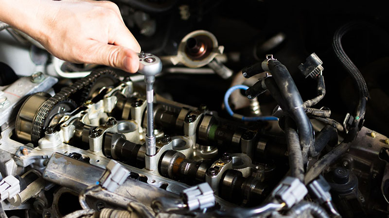 Car mechanic repairing an internal combustion engine, focusing on maintenance and repairs.
