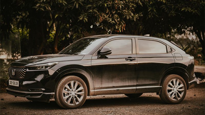 Grátis Um elegante SUV Honda HR-V preto estacionado ao ar livre entre árvores em um dia ensolarado