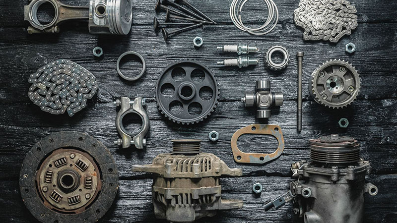 Car spare parts arranged on a black wooden workbench, flat lay view.