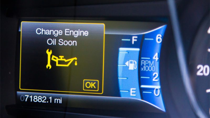 Mensagem de alerta "Troque o óleo em breve" no painel do carro.