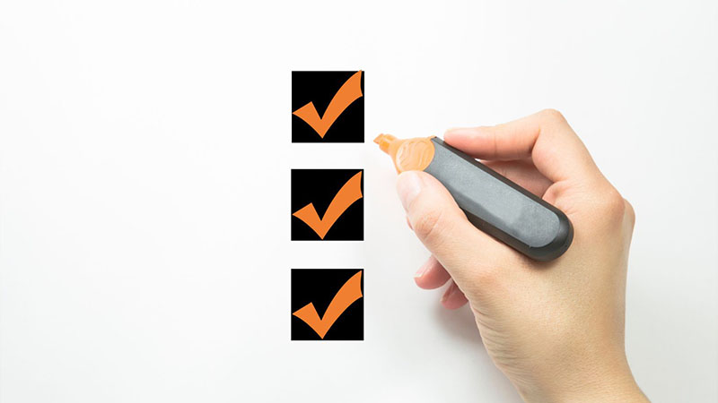 Person checking items on a checklist, representing supplier evaluation and engine sourcing review process.