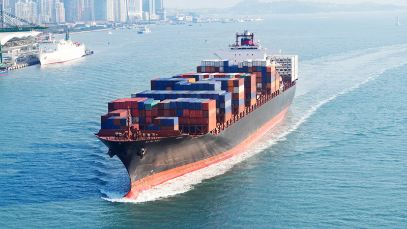 Large container ship sailing across the sea, symbolizing global logistics and timely engine delivery to customers.