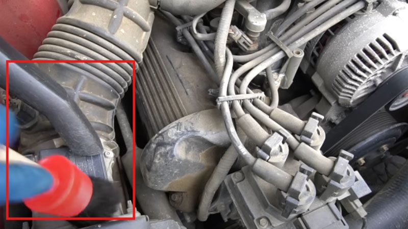 Using a vacuum and a brush to dry-clean the engine bay.