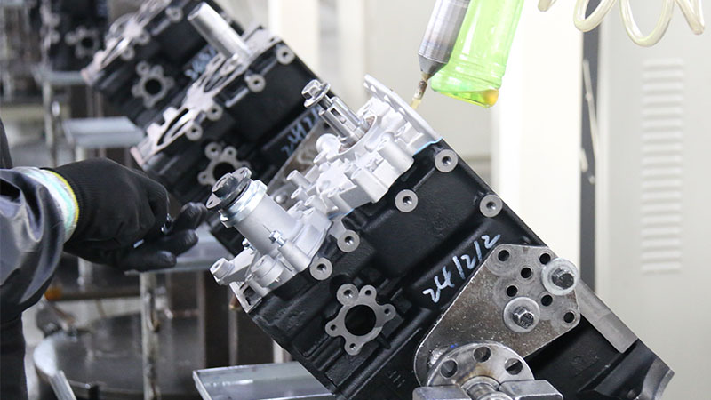 Mechanic working on automotive engine assembly during production process.