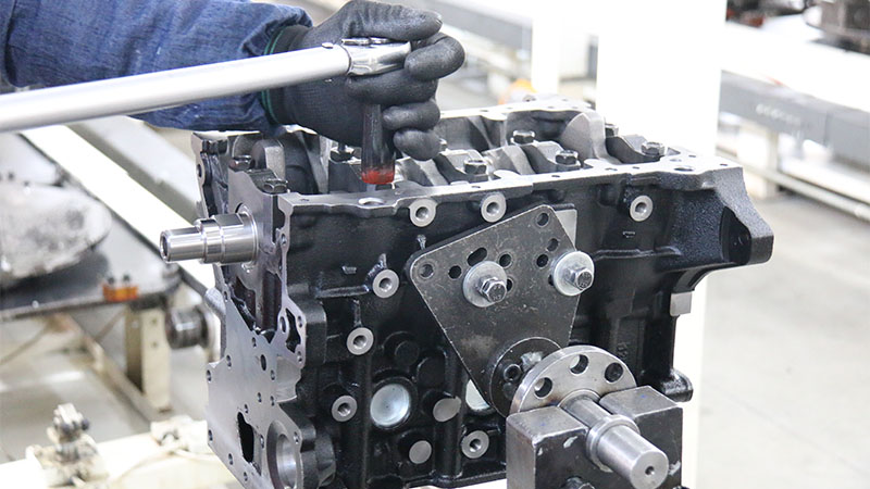 Close-up view of mechanic’s hand working on automotive engine assembly.