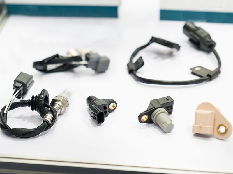 Close-up of camshaft position sensor and other sensors displayed for automotive industry use.