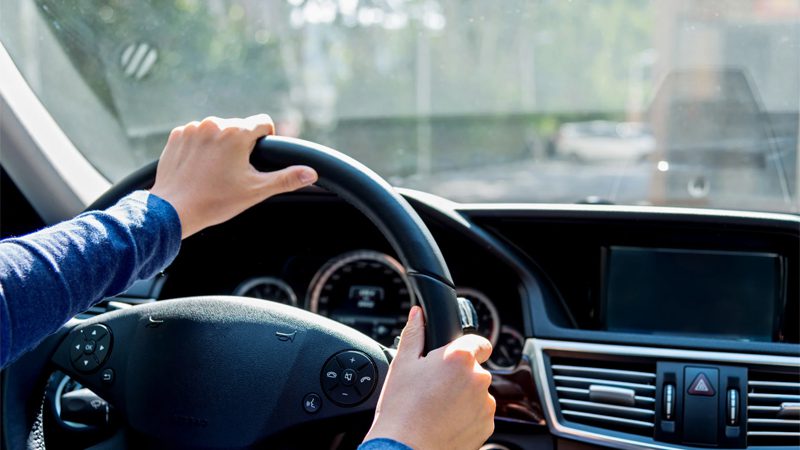 Two hands gripping the steering wheel, capturing the experience of driving and vehicle control.
