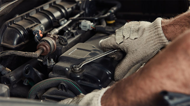 Technician inspecting a diesel engine in a car repair workshop.