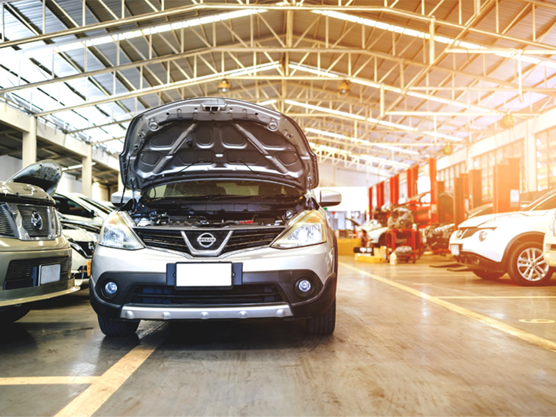 Nissan cars in a service center with the car hood lifted up, showcasing engine maintenance and repairs.