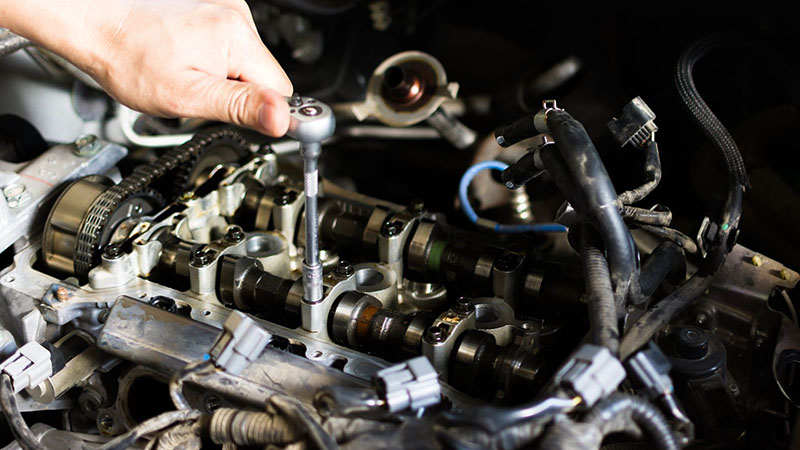 Car mechanic repairing an internal combustion engine in an automotive workshop.